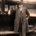 A 1920s bootlegger in front of a car.